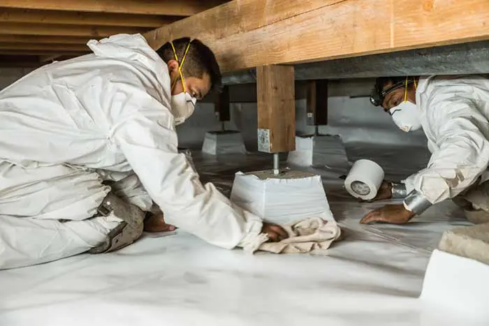 Workers sealing crawl space with vapor barrier