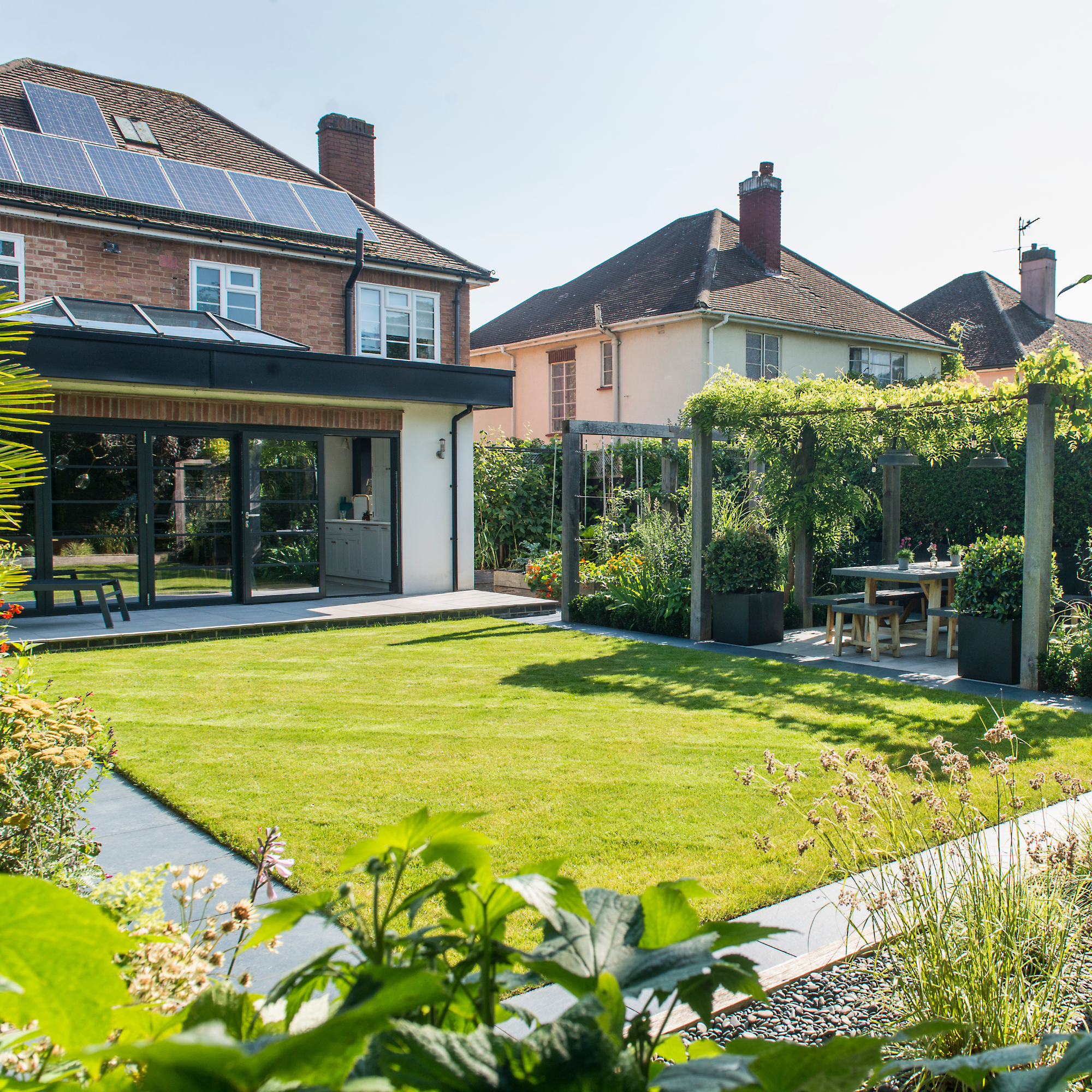 Soggy Ground Repair Services by Us - DMV Area 2 Modern garden with a spacious lawn, outdoor seating area, and solar panels on the house roof.