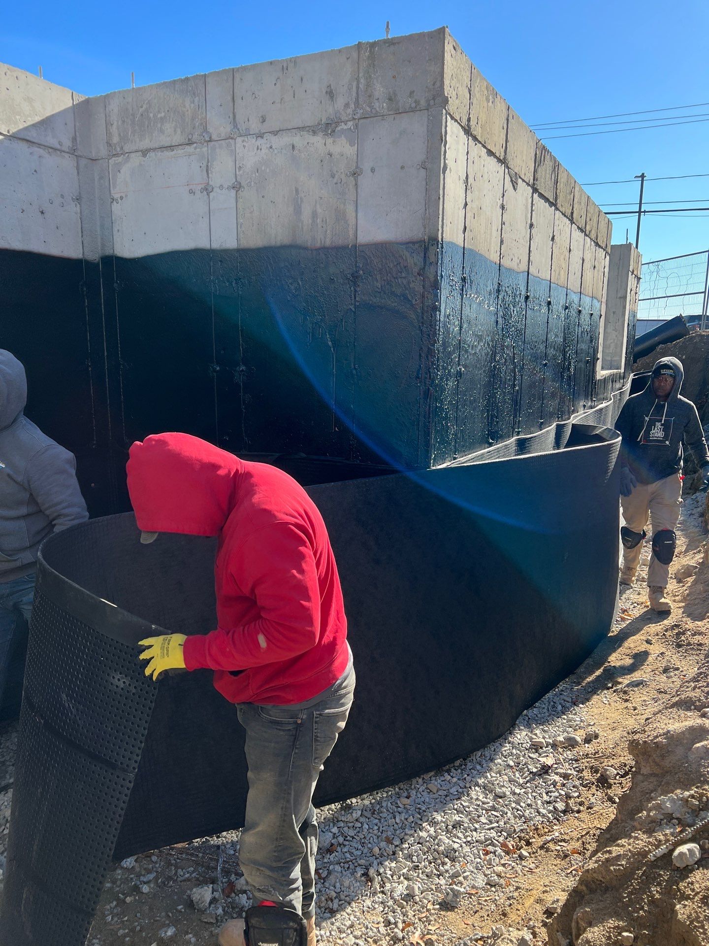 Water Runoff Solutions in DC, MD, VA - Our Services 3 Workers applying waterproof membrane on foundation wall for protection against moisture