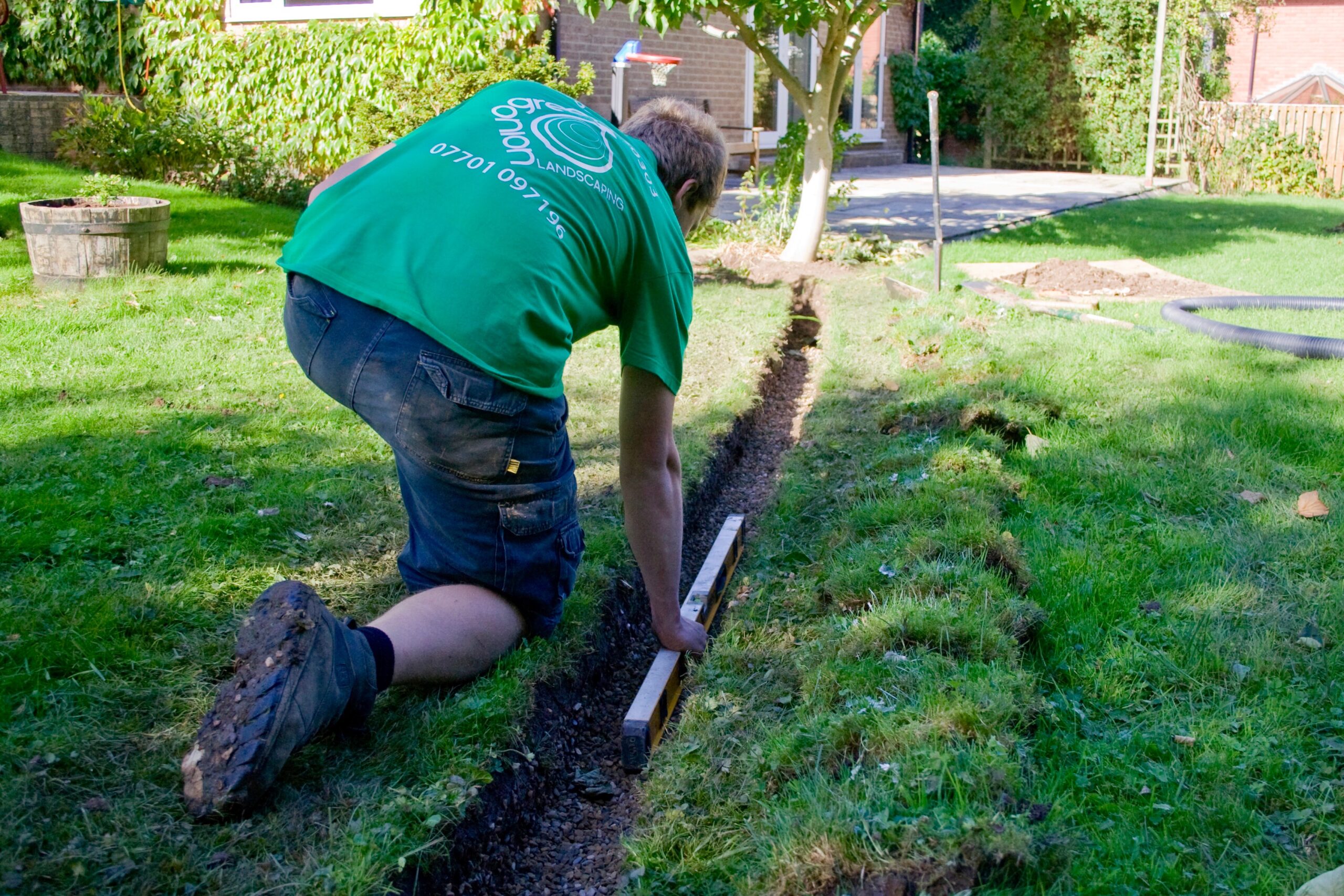 Soggy Ground Repair Services by Us - DMV Area 3 Professional landscaping worker leveling the trench for drainage installation.