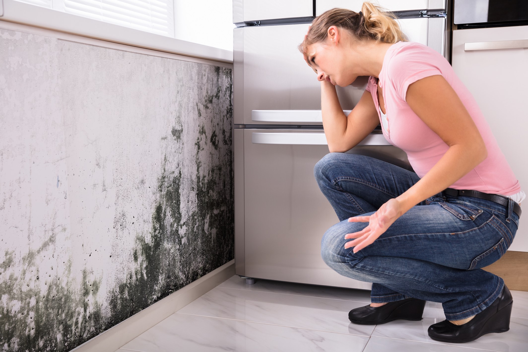 Mold Remediation Experts: Restore Your Home with Professional Mold Remediation Services 2 A worried woman looking at mold growing on the wall of her home.