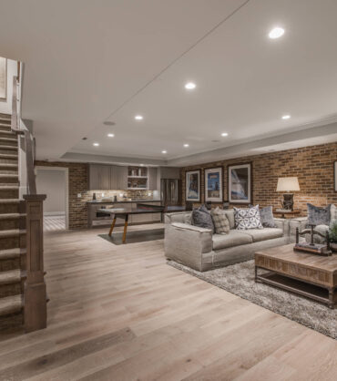 Finished basement with modern living area, sectional sofas, and a home bar