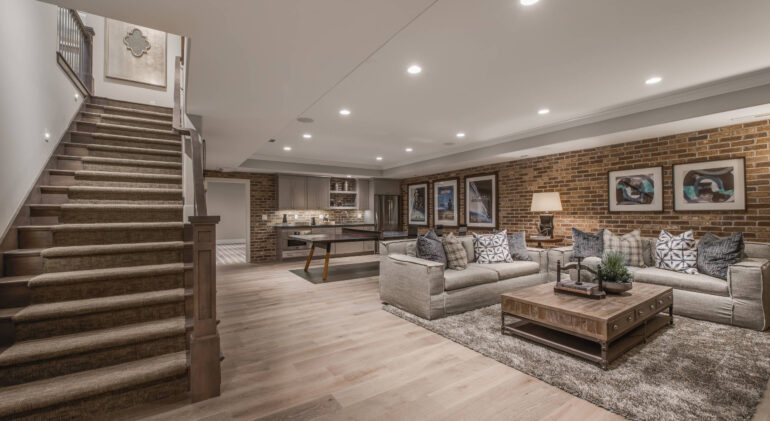 Finished basement with modern living area, sectional sofas, and a home bar
