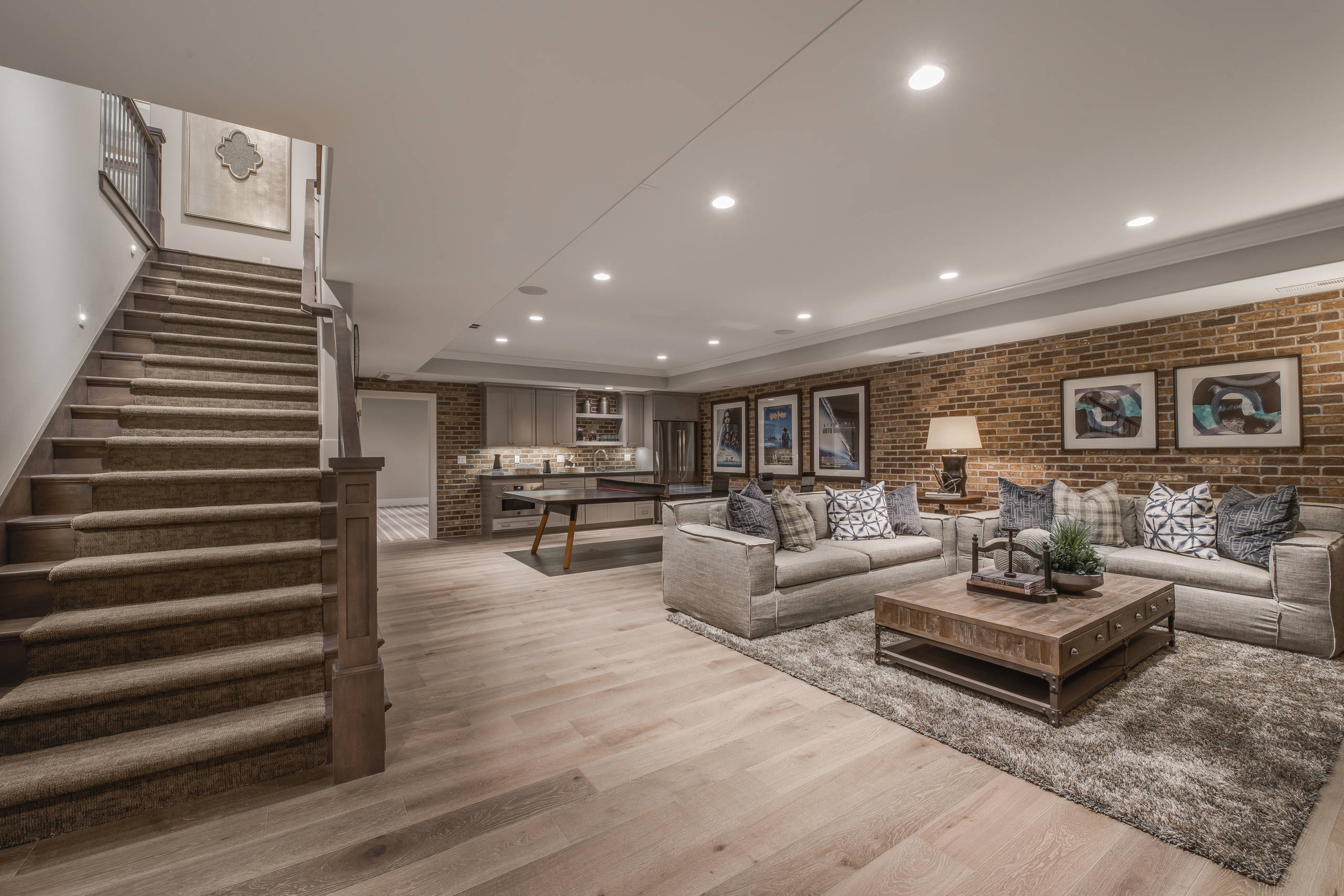 Finished basement with modern living area, sectional sofas, and a home bar