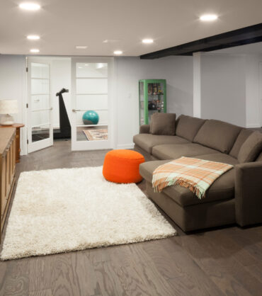 Finished basement living space with sectional sofa, TV, and exercise room