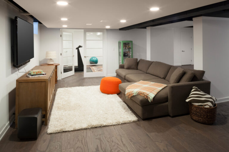 Finished basement living space with sectional sofa, TV, and exercise room