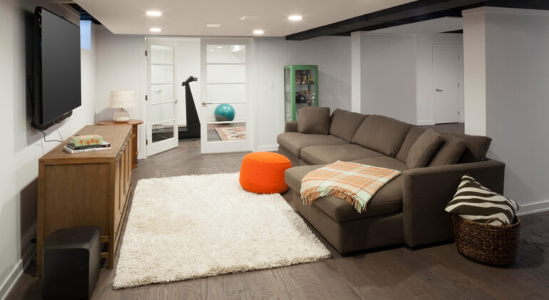 Finished basement living space with sectional sofa, TV, and exercise room