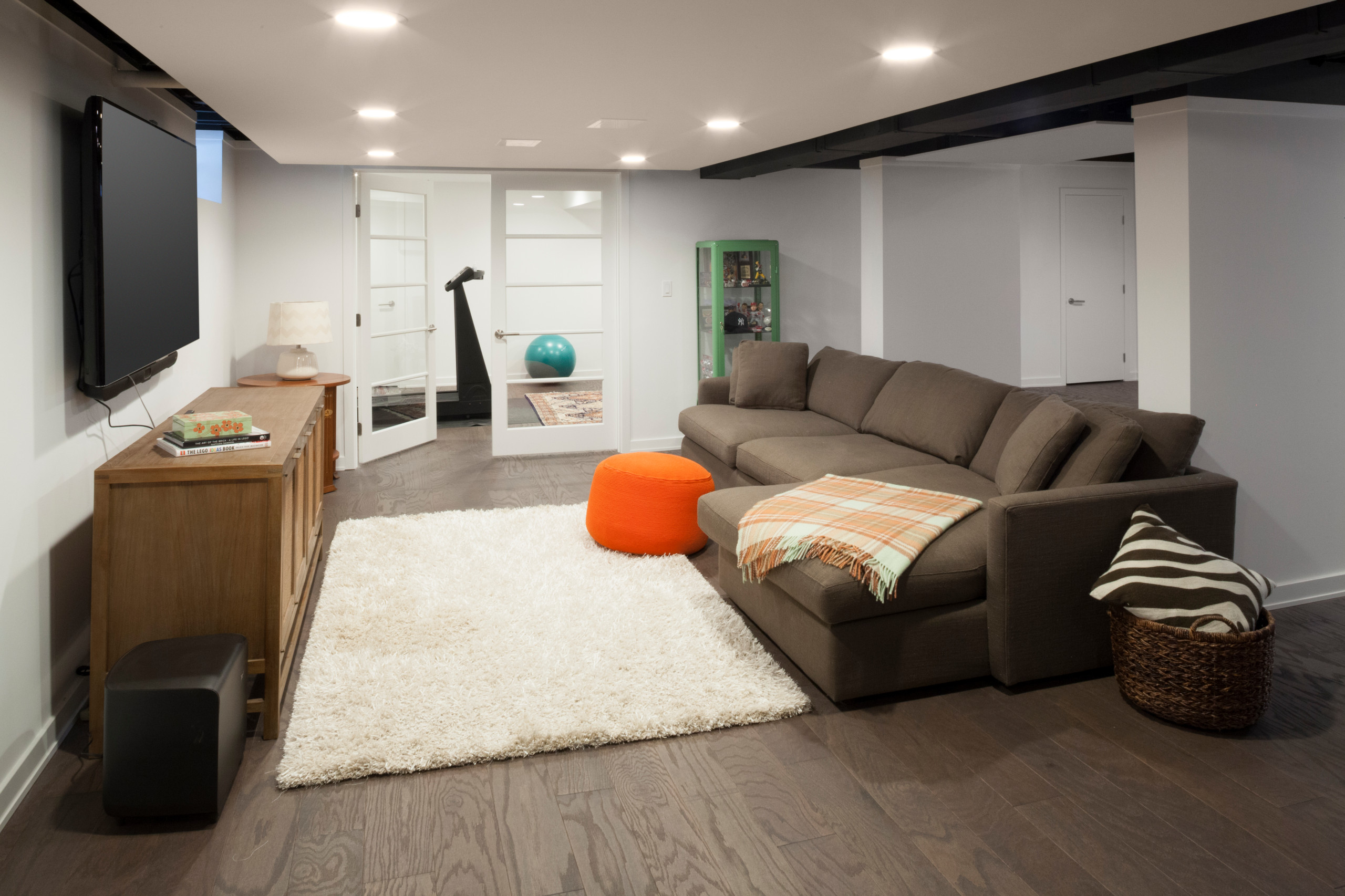 Finished basement living space with sectional sofa, TV, and exercise room