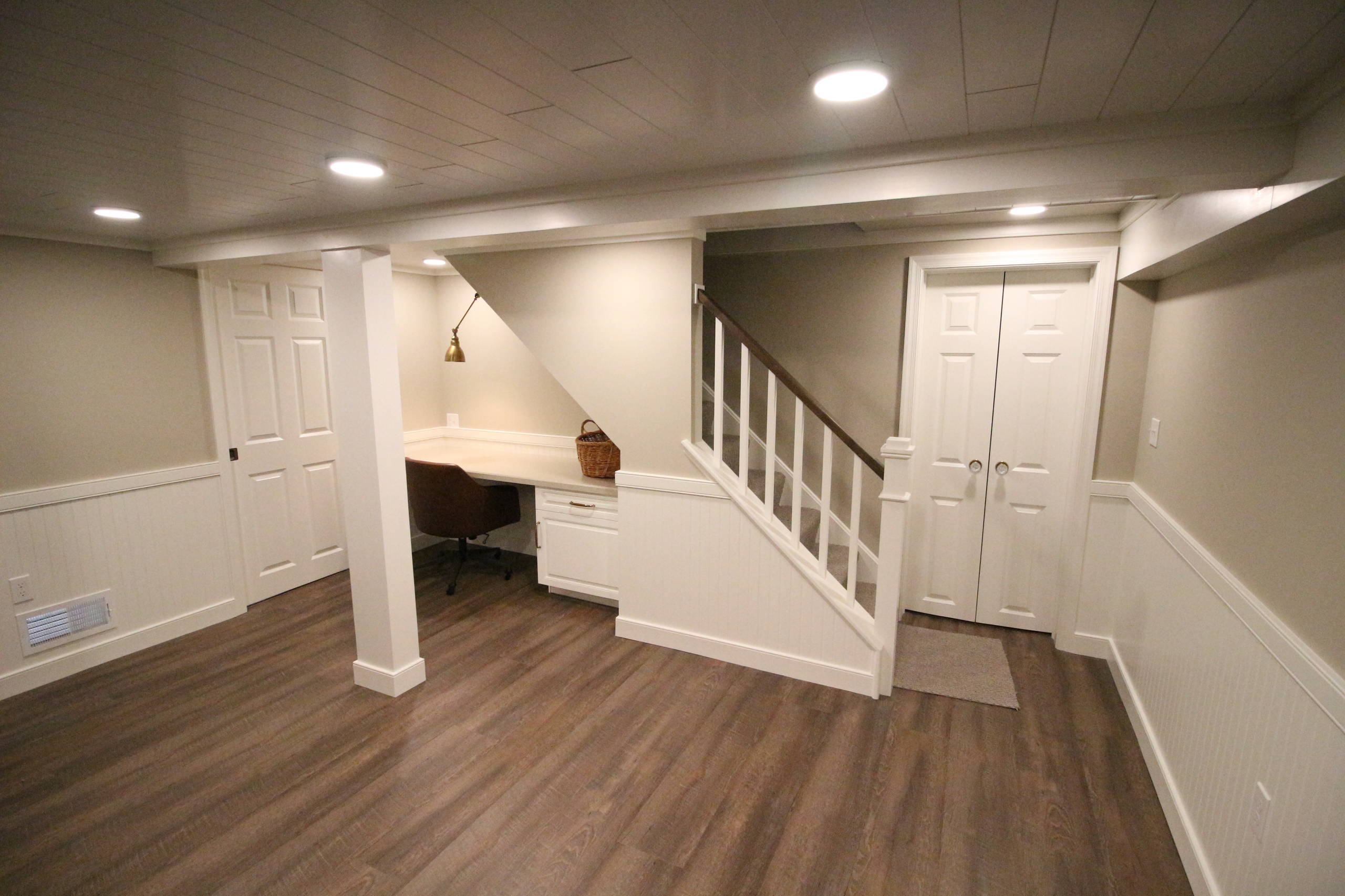Reliable Wet Basement Specialists - Trusted Solutions 4 Modern basement with a cozy workspace, stairs, and light wood flooring.