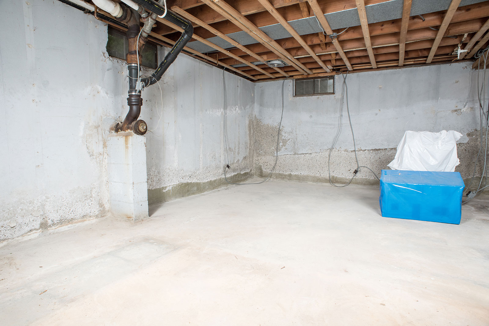Unfinished basement with exposed pipes and unsealed walls.