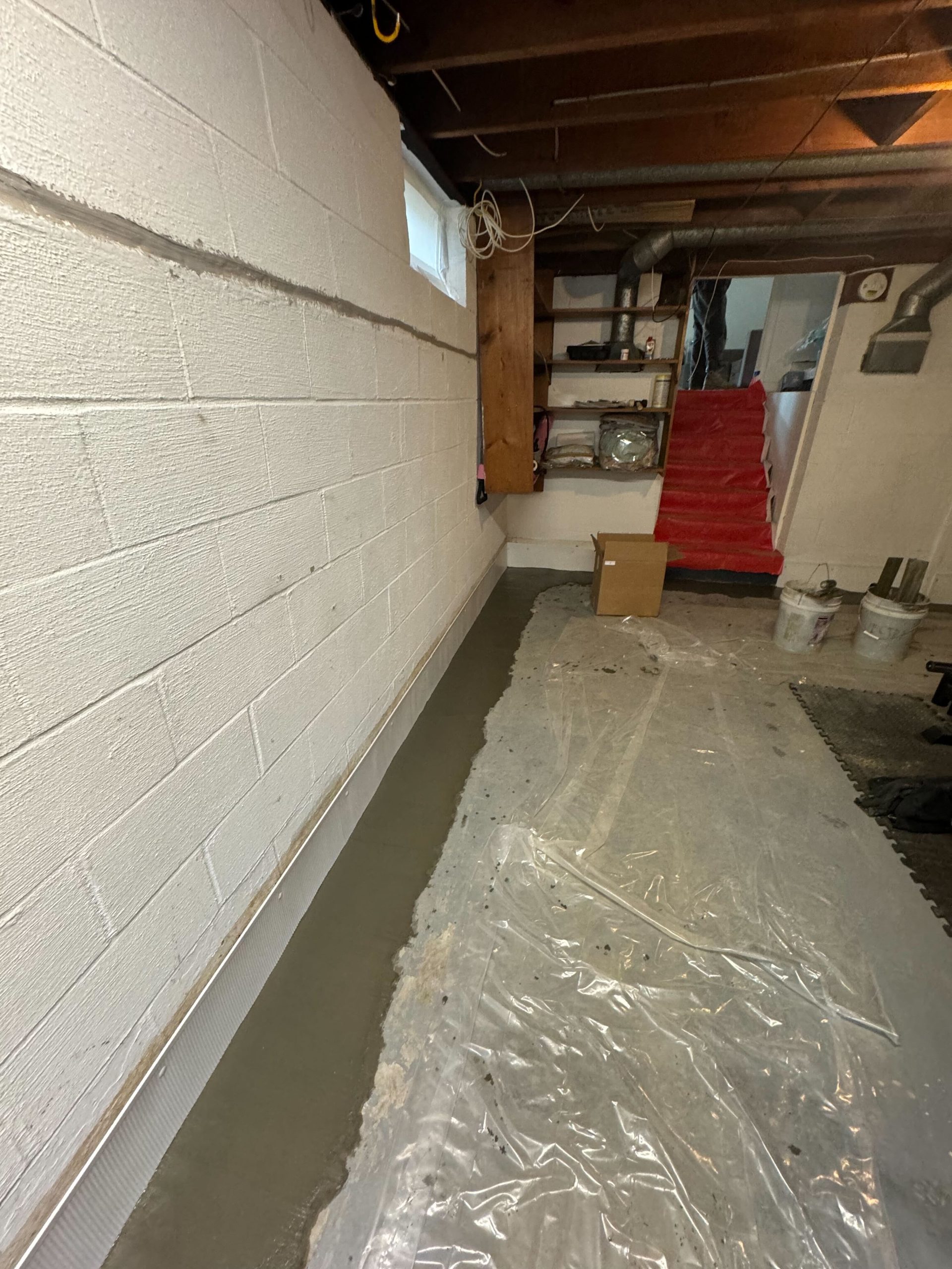 Basement waterproofing system installed along wall base.