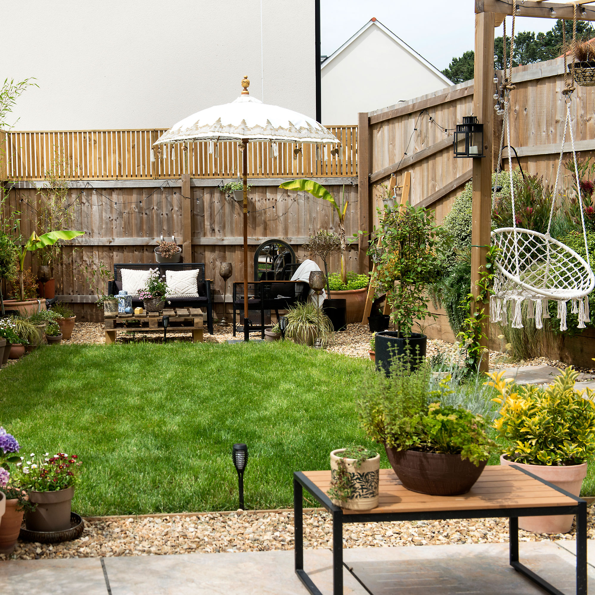 Yard Drainage: Prevent Flooding & Keep Your Lawn Thriving with Sustainable Stormwater Management 3 Beautifully landscaped backyard with green grass, potted plants, outdoor seating, and a white garden umbrella.