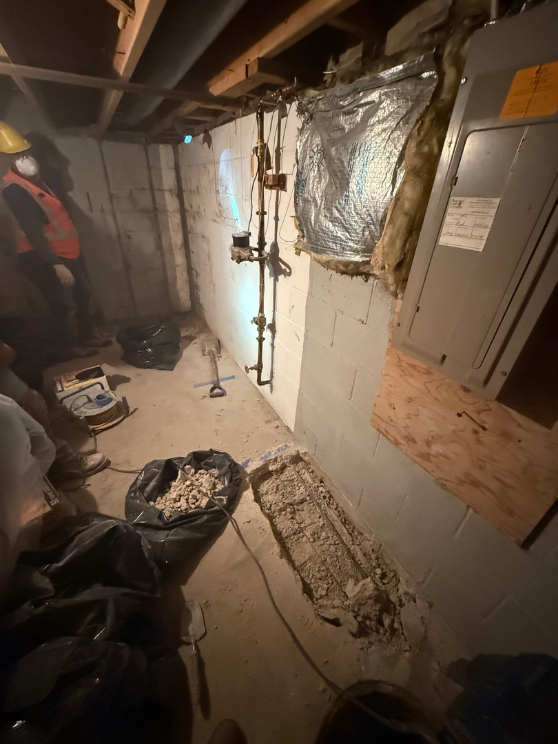 Crew opening the basement slab at the footing along the foundation corner — Silver Spring, MD