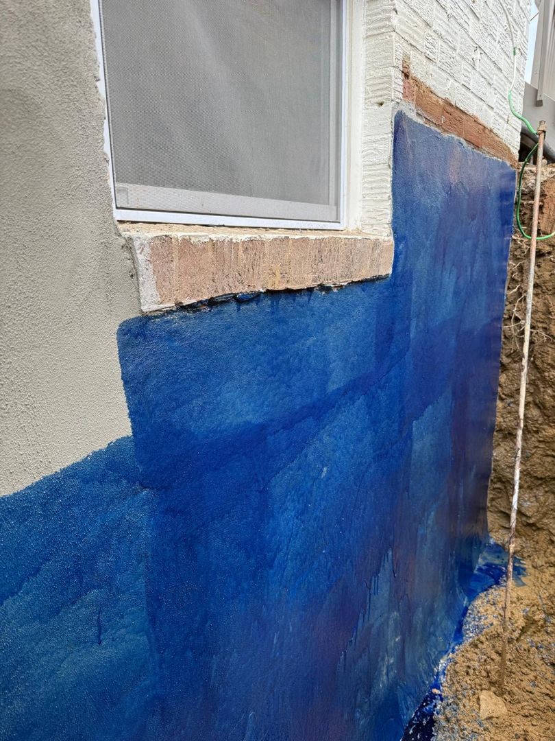 Blue liquid waterproofing layer on the foundation wall