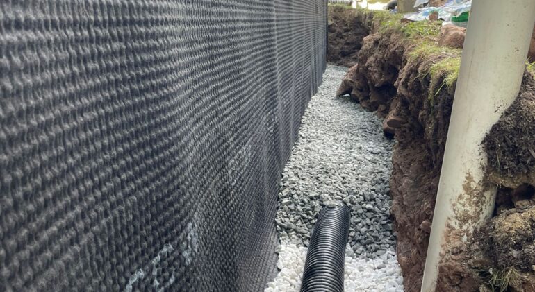 Wet Carpet in a Basement Bedroom: Sealing an Ashburn Foundation From the Outside 1 Exterior drain tile in clean stone alongside the drain board — Ashburn, VA