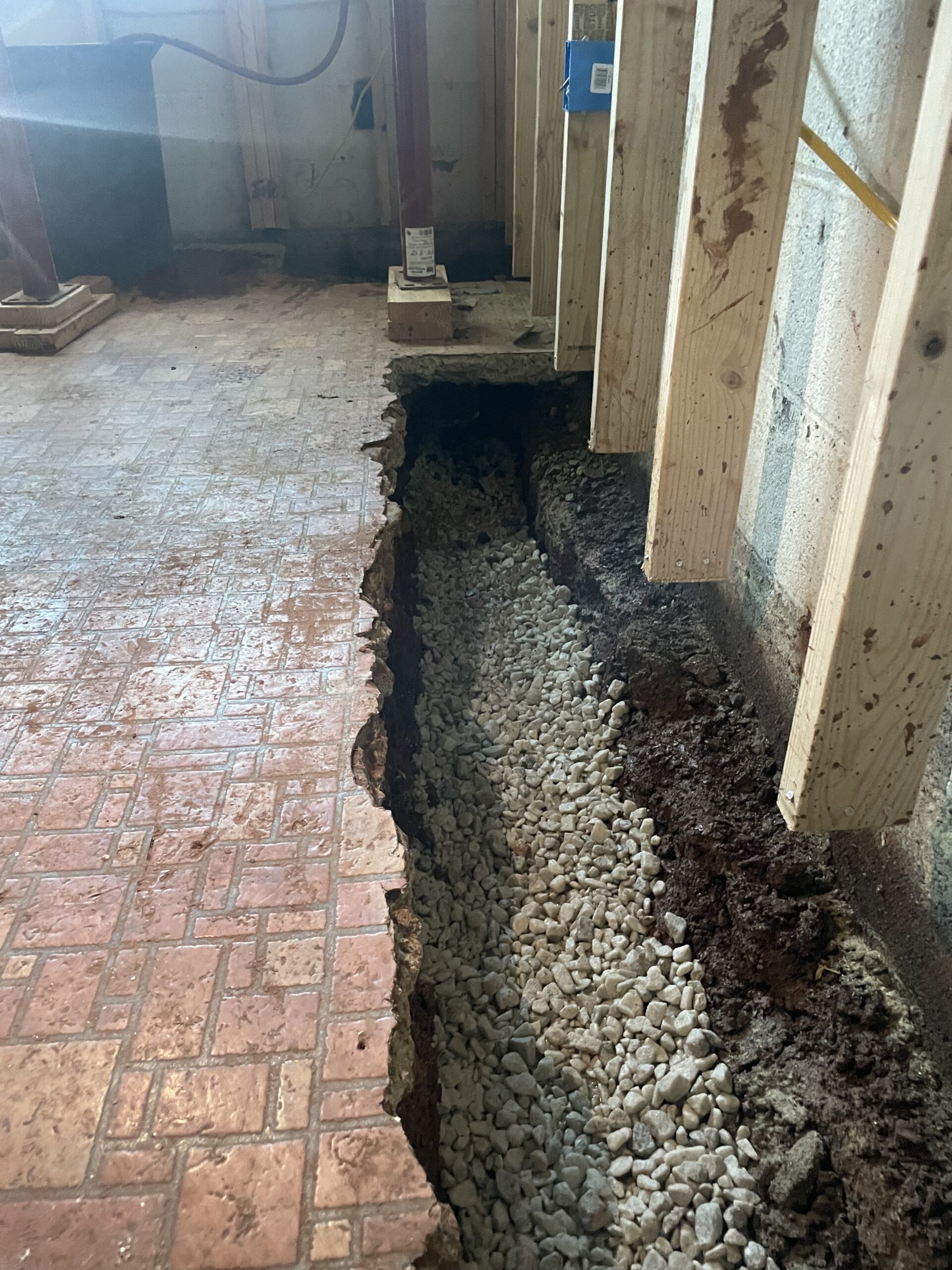 Interior French drain pipe bedded in clean gravel in the footing trench — Manassas basement