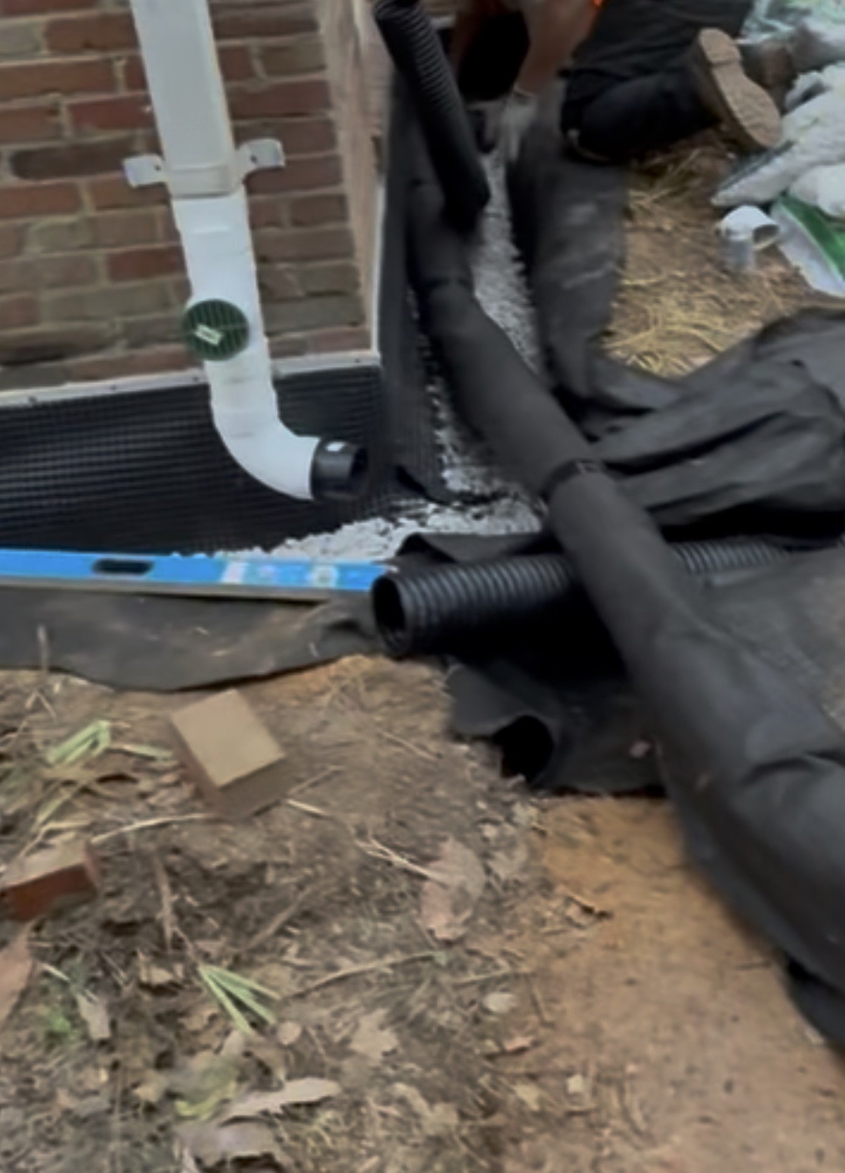A downspout buried and tied into exterior drainage with a French drain to carry roof water away from the foundation