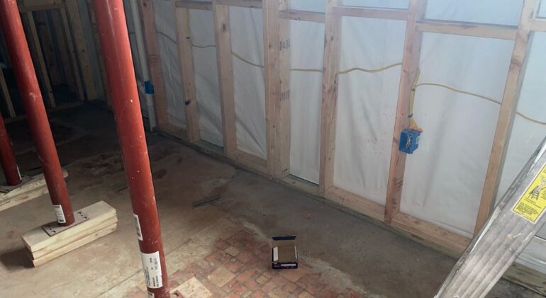 When You Can't Cut the Whole Slab at Once: A High-Water-Table Basement off I-66 in Manassas 2 Dried, reinforced large basement with wall vapor barrier and steel support posts — Manassas, VA