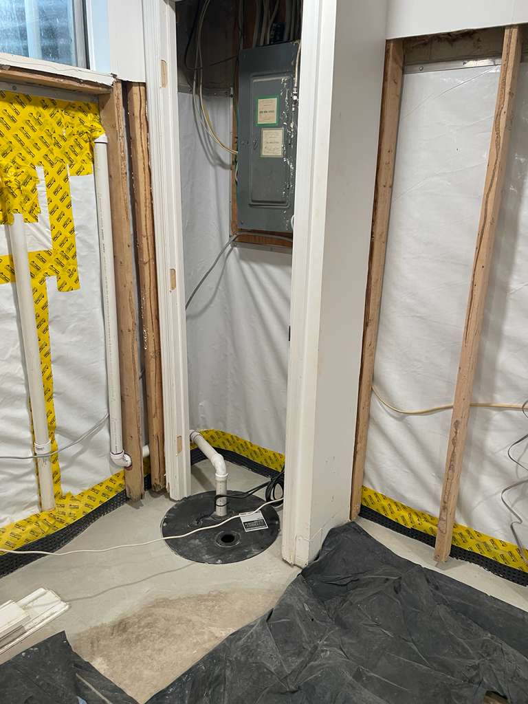After — interior French drain, dimple-board drainage and a new white vapor barrier installed along the basement walls