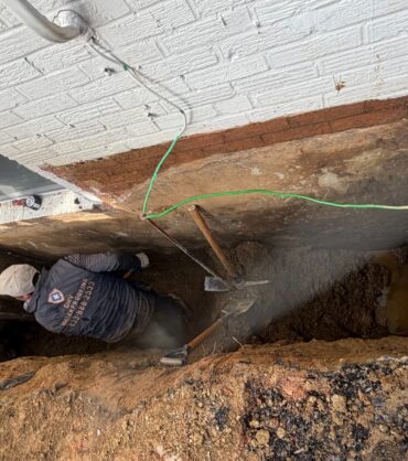 A DMV Waterproofing crew member excavating along a brick foundation wall down to the footing in Northwest DC