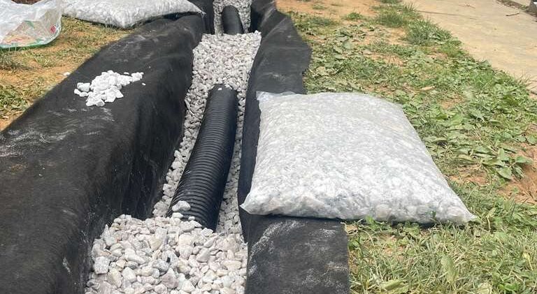 Six-inch perforated pipe bedded in #57 washed stone inside the geotextile wrap — North Potomac, MD