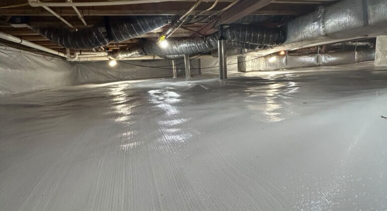 Finished crawl space encapsulation with a sealed barrier across the floor and up the walls, steel support columns in place
