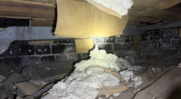 The Draft Was Coming From Underneath: A Germantown Crawl Space 1 Fiberglass insulation batts hanging loose and fallen from crawl space floor joists onto an old plastic sheet below