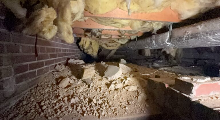 We Took the Insulation Out: A Southwest DC Crawl Space 2 Fiberglass batts sagging out of the floor joists in a vented crawl space, over a bare dirt and rubble floor beside a brick foundation wall