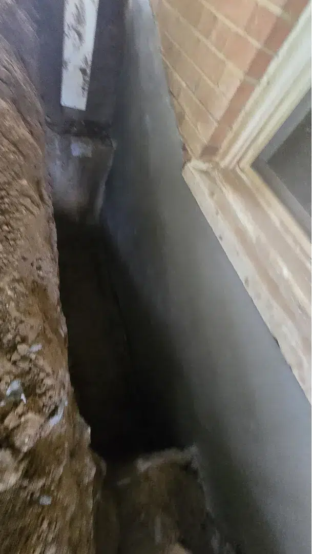 Cementitious waterproofing coat on the exposed foundation wall beneath a deck in Kensington, Maryland