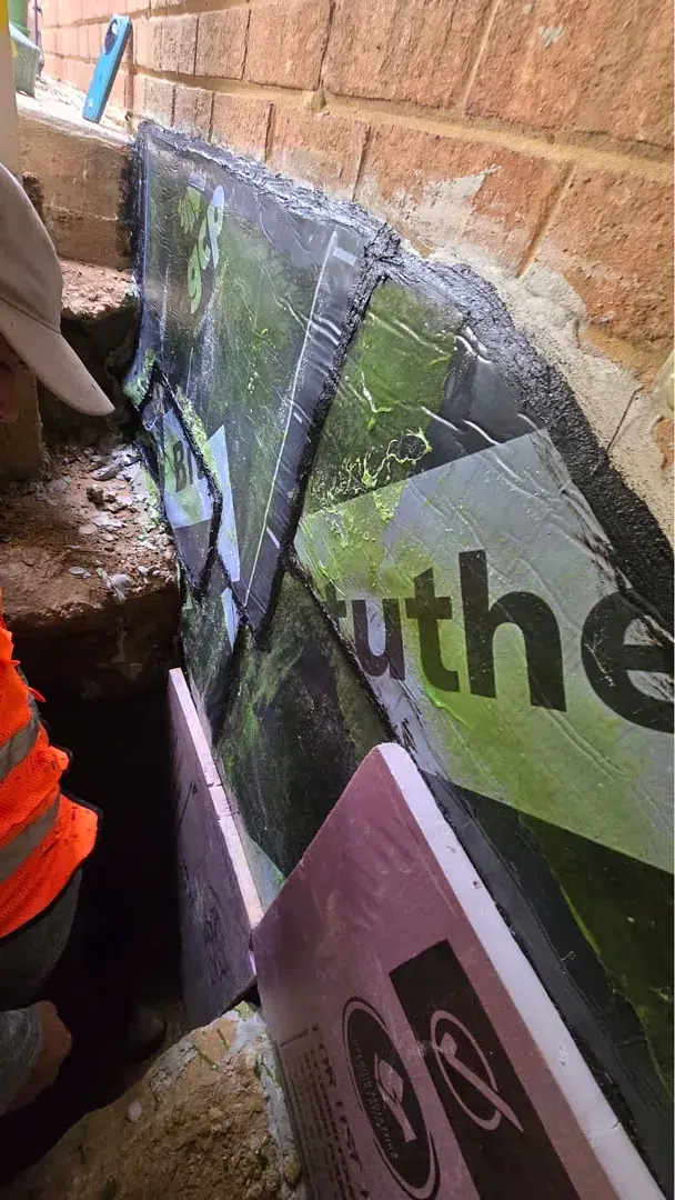 Self-adhered exterior waterproofing membrane and pink XPS protection at a Kensington foundation