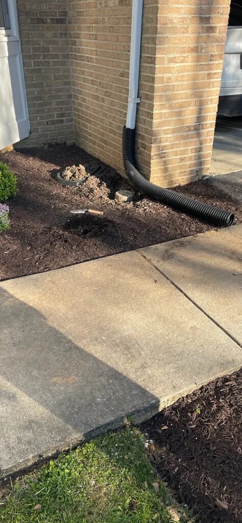 Buried Downspouts in Rockville, MD: Two Runs and a Pop-Up 1 Before-work downspout and flexible surface extension beside a Rockville garage walkway