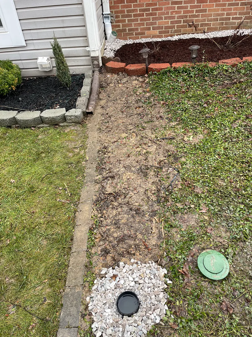 Exterior French Drain and Buried Downspout in Silver Spring, MD: A Real Front-Yard Project 3 Gravel and pop-up discharge components in the yard during the exterior drainage project