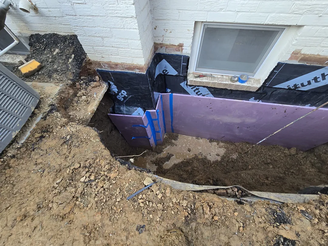 Bethesda, MD Foundation Leak: Exterior Waterproofing and Grading Tile 3 Black waterproofing sheet membrane and purple XPS protection boards during installation