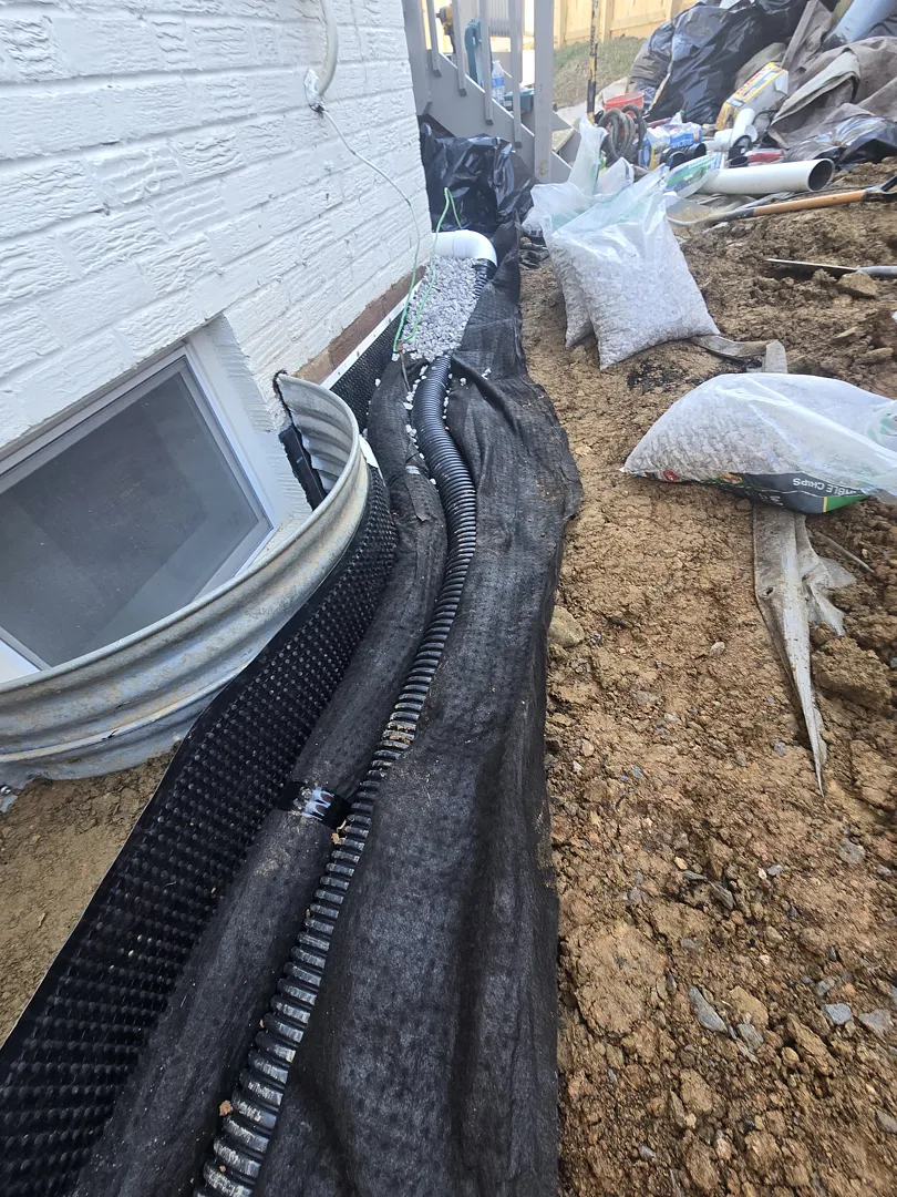 Bethesda, MD Foundation Leak: Exterior Waterproofing and Grading Tile 4 Near-grade perforated grading tile in gravel and geotextile beside the Bethesda wall