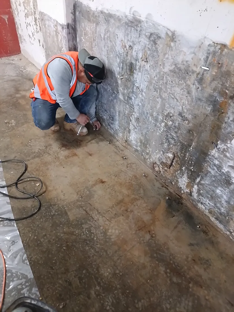 Foggy Bottom, DC Basement Wall Crack Injection: Real Repair Photos 1 Crew member working at the lower basement wall during a localized Foggy Bottom, DC repair
