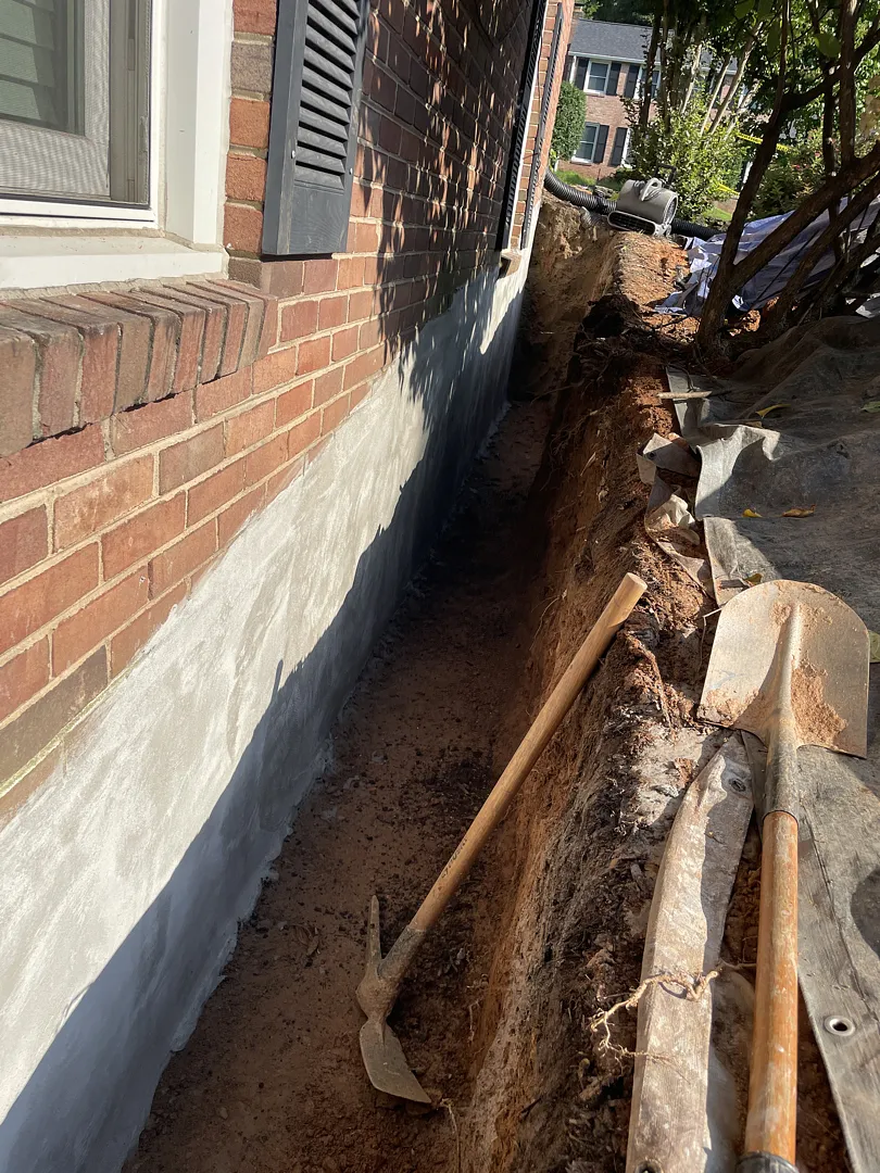 Potomac, MD Exterior Waterproofing Beside a Brick Foundation 1 Exposed Potomac foundation wall with gray coating during exterior waterproofing work