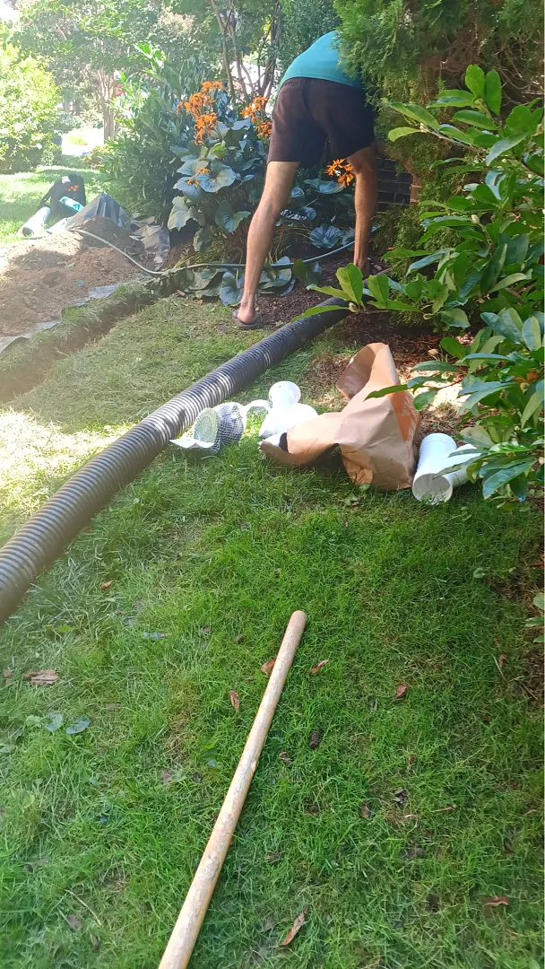 Pipe staged on lawn beside a crew member during the later Rockville downspout job