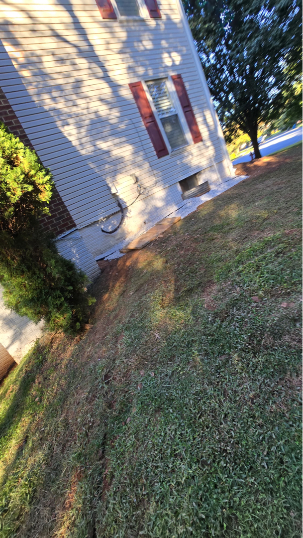 Side-yard view of the Sterling house and foundation area documented for the exterior waterproofing job