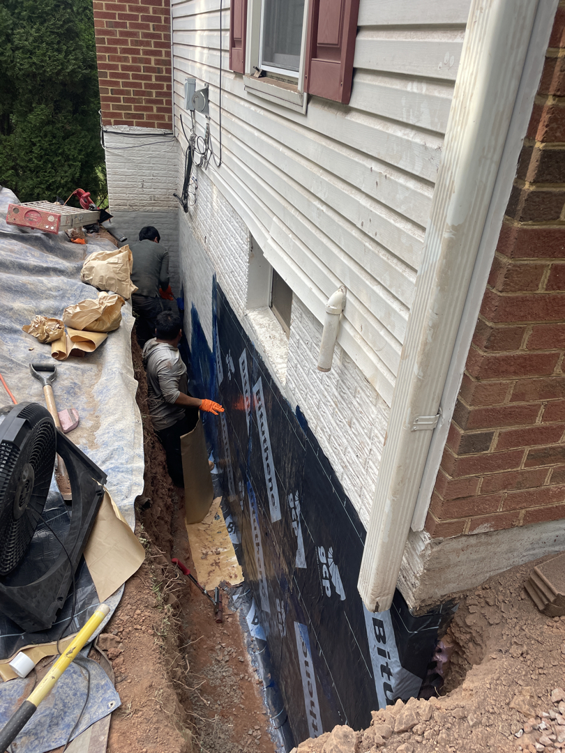 Crew applying self-adhered sheet membrane to the excavated Sterling foundation wall