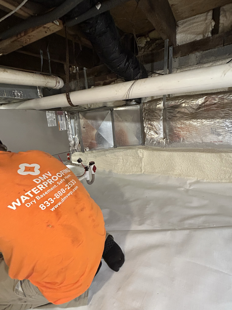 Crew sealing the new reinforced floor vapor barrier to the crawl space wall liner