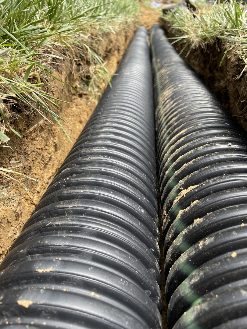 Two pipe runs laid in a narrow trench beside the Bethesda home