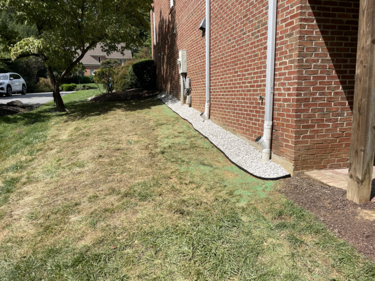 Completed Bethesda exterior waterproofing with gravel drainage strip and restored grade