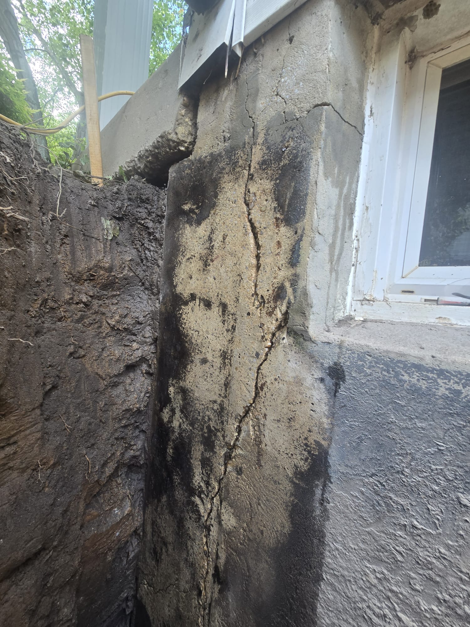 Exterior Waterproofing in Rockville, MD: Windowed Foundation Wall Case 3 Crack in the exposed exterior foundation wall beside a Rockville basement window before waterproofing