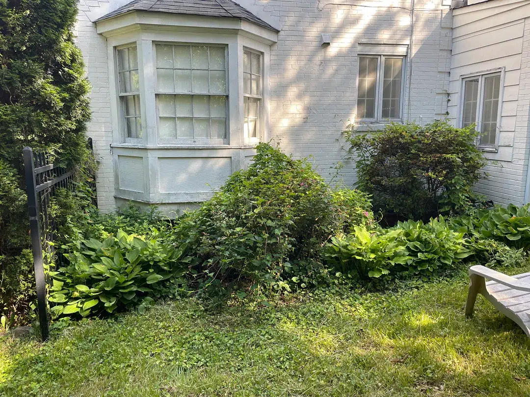 Bethesda Exterior Waterproofing Around a Basement Window Well 1 Landscaped white-brick Bethesda home before exterior foundation waterproofing