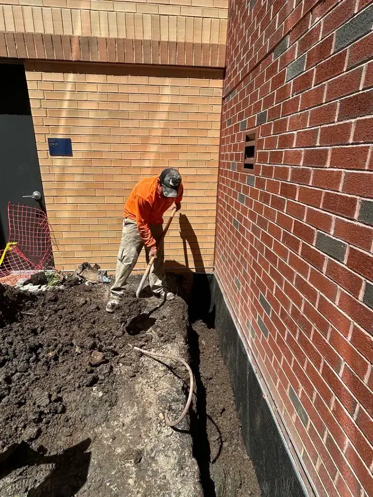 Full-depth excavation beside a brick foundation wall in Bethesda, Maryland