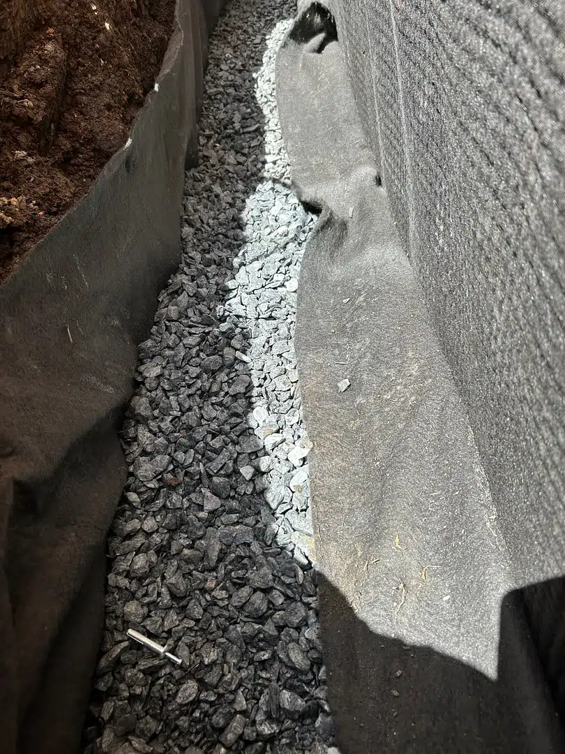 Clean gravel and geotextile at the bottom of a deep foundation trench in Bethesda