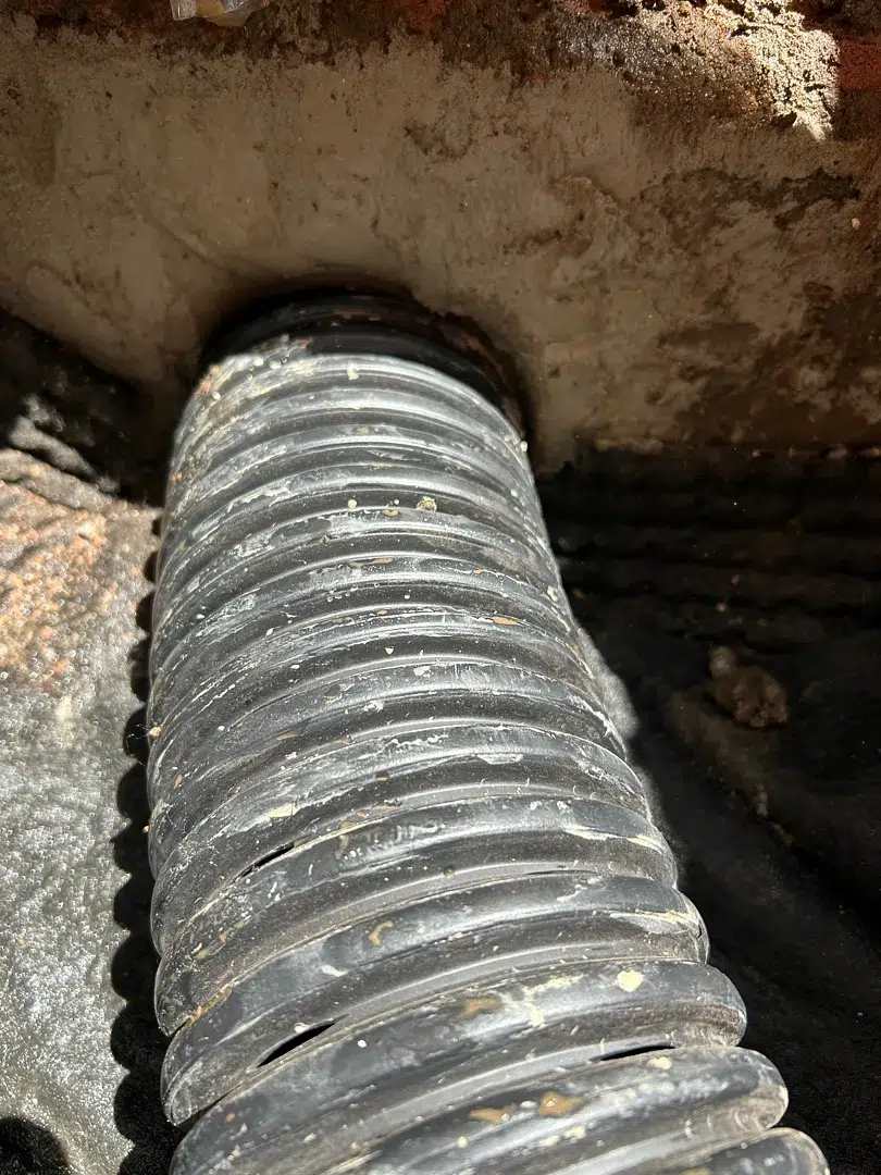 Close-up of perforated drain pipe documented in a Bethesda footing-drain installation