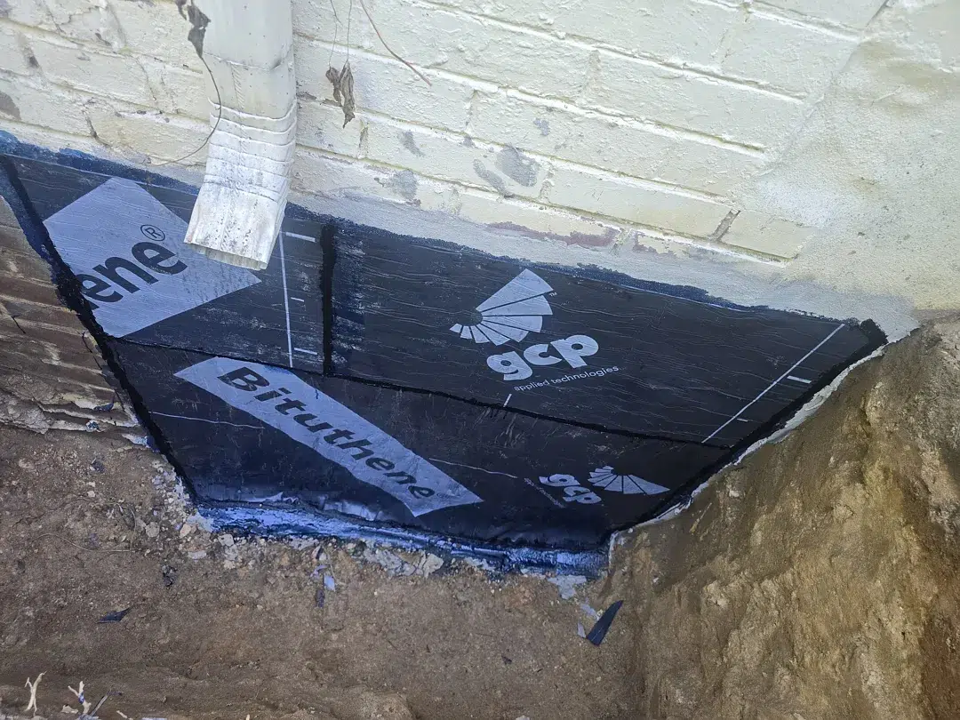 Bethesda Exterior Waterproofing Around a Basement Window Well 4 Near-grade sheet membrane sloping away from a Bethesda brick foundation wall