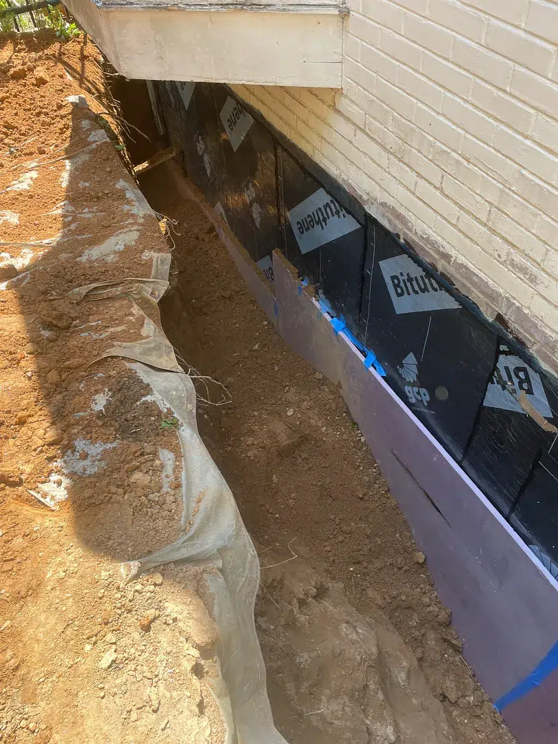 Bethesda Exterior Waterproofing Around a Basement Window Well 3 Black sheet membrane and purple XPS protection on a deeply excavated Bethesda foundation wall