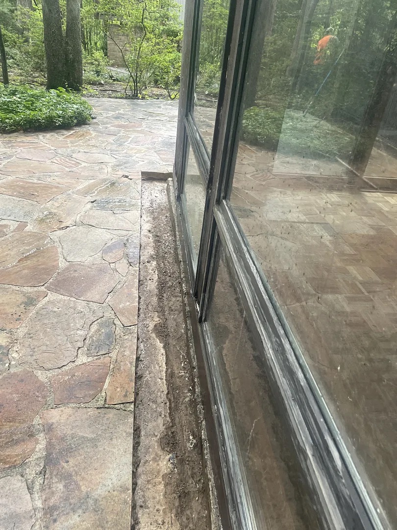 Narrow original strip between basement-extension glazing and a stone patio in Potomac